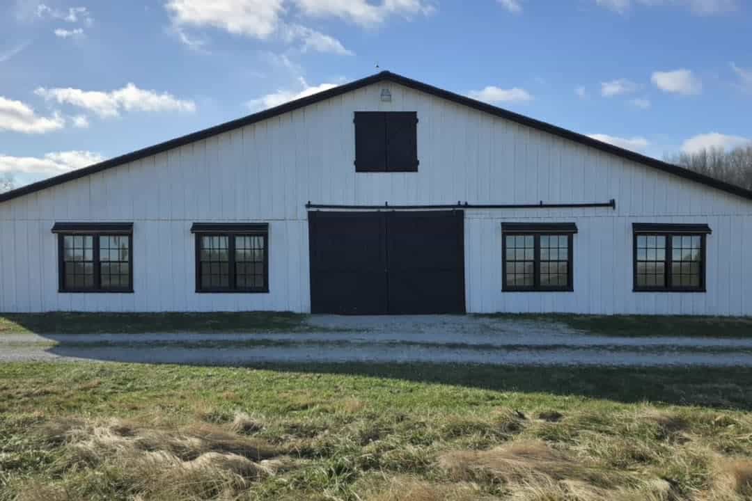 The white barn with black double doors and cupola at Highland Oaks Weddings and Events in Palmyra, Indiana, a barn wedding venue about forty minutes from Louisville