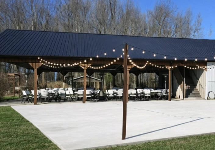 String lights over the covered reception pavilion with tables set at Highland Oaks in Palmyra, Indiana, where the wedding bar is set up