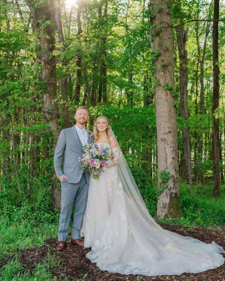 Bride and groom standing among tall trees at the Highland Oaks forest ceremony site in Palmyra, Indiana